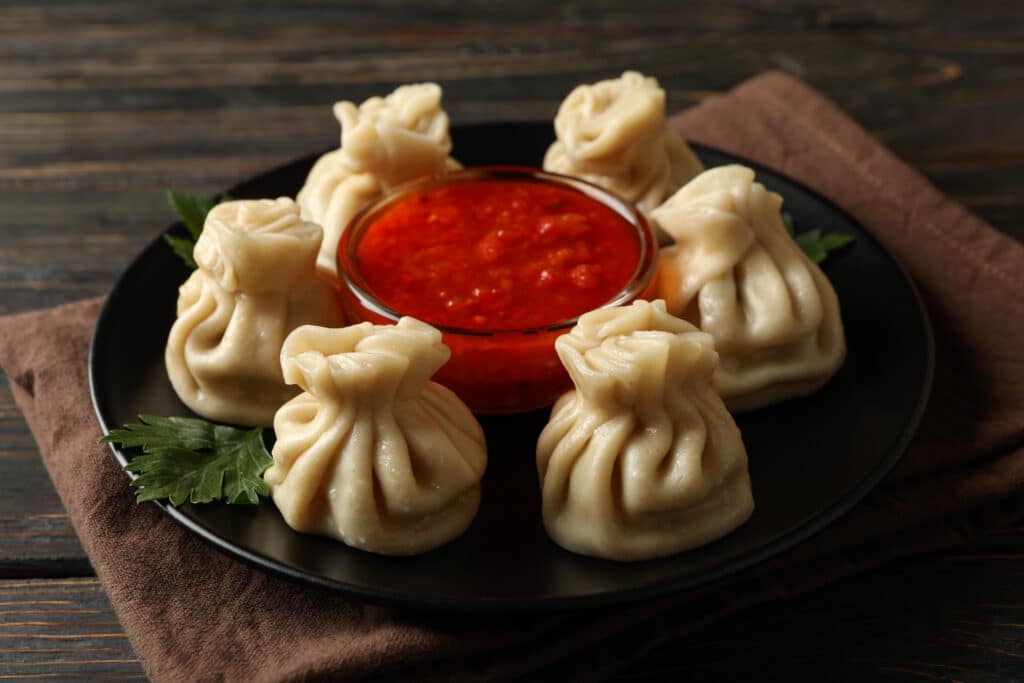 Hot, Steamy & Irresistible Momos in Clayton | Tiffin Box 2 concept of tasty lunch with plate of khinkali and 2025 03 25 02 05 05 utc